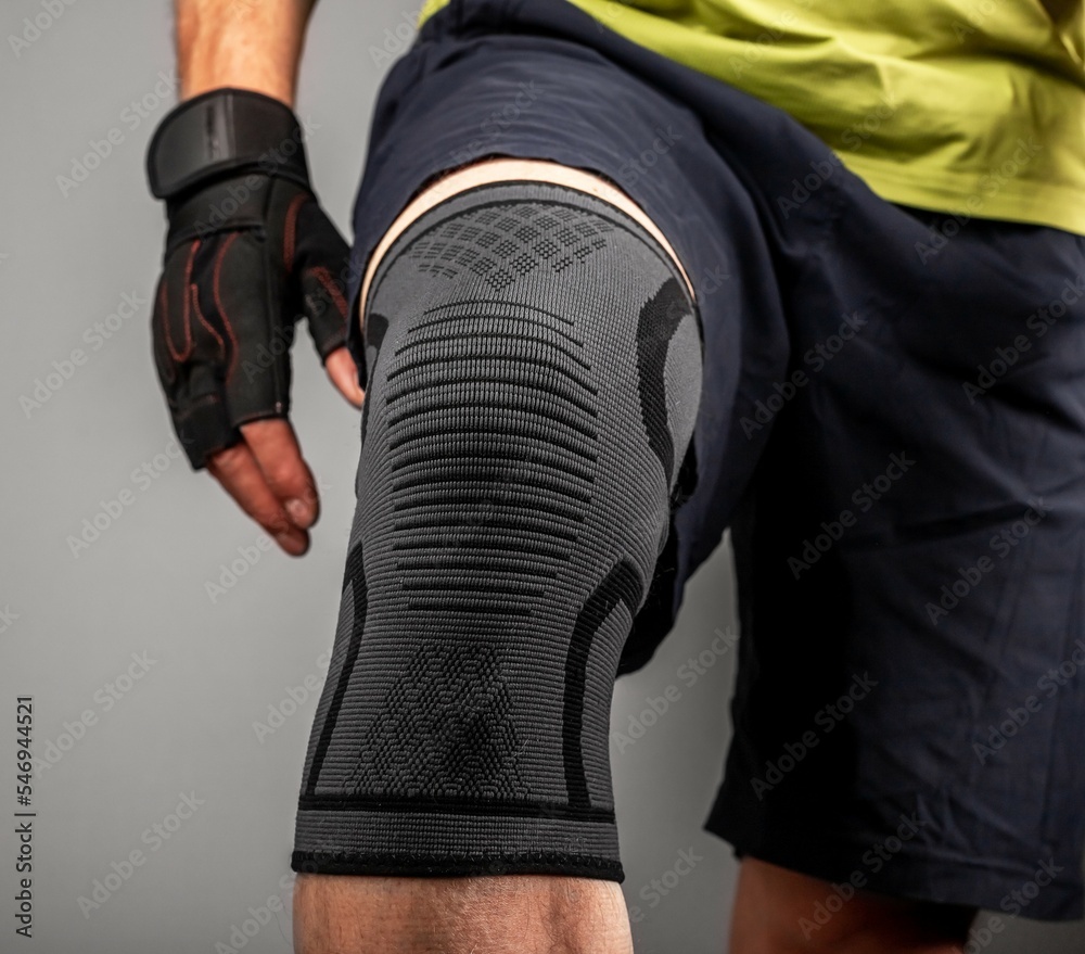 Athlete bodybuilder leg closeup, wearing knee support brace, elastic