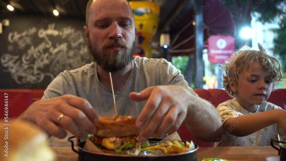 Caucasian bearded middle-aged man with an appetite eating burger and fast food in cafe or restaurant. Burger is not helpful food. Very hungry guy. Concept of unhealthy food, snack, street food. Caucasian bearded middle-aged man with an appetite eating burger and fast food in cafe or restaurant. Burger is not helpful food. Very hungry guy. Concept of unhealthy food, snack, street food.