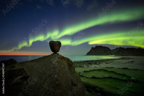 Aurora borealis dancing above a heart shaped rock on Uttakleiv beach in Lofoten, Norway photo