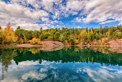 Scenic view of mirror like reflection of Carces lake in south of France in autumn colors against dramatic sky photo