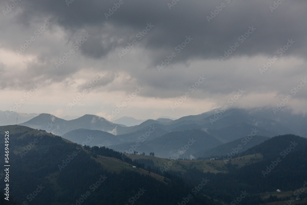 Dark forest mountain range in a misty gray deep fog in the Carpathians mountains, Chornogora, Ukraine