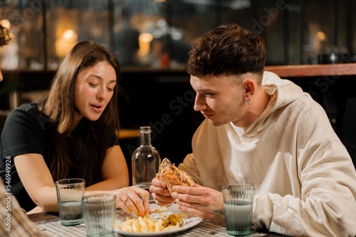 a group of friends chatting at a table in a restaurant, eating a burger and french fries