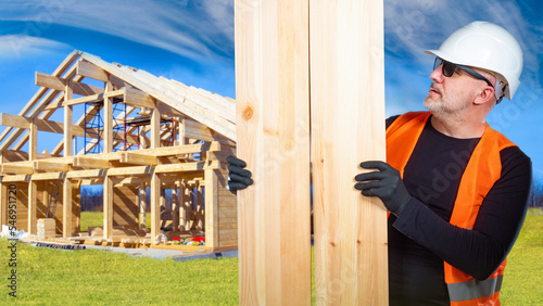 Wallpaper Mural Man builder. Guy considers boards for construction. Man builder in sunglasses builds house. Male near framed wooden cottage. Construction company worker under summer sky. Builder building frame house Torontodigital.ca
