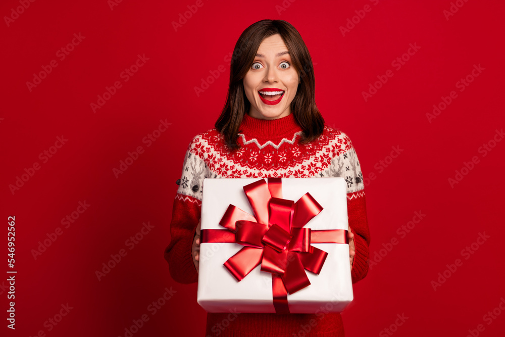 Photo of ecstatic overjoyed astonished girl with straight hairstyle wear red sweater hold gift box isolated on red color background Photo of ecstatic overjoyed astonished girl with straight hairstyle wear red sweater hold gift box isolated on red color background