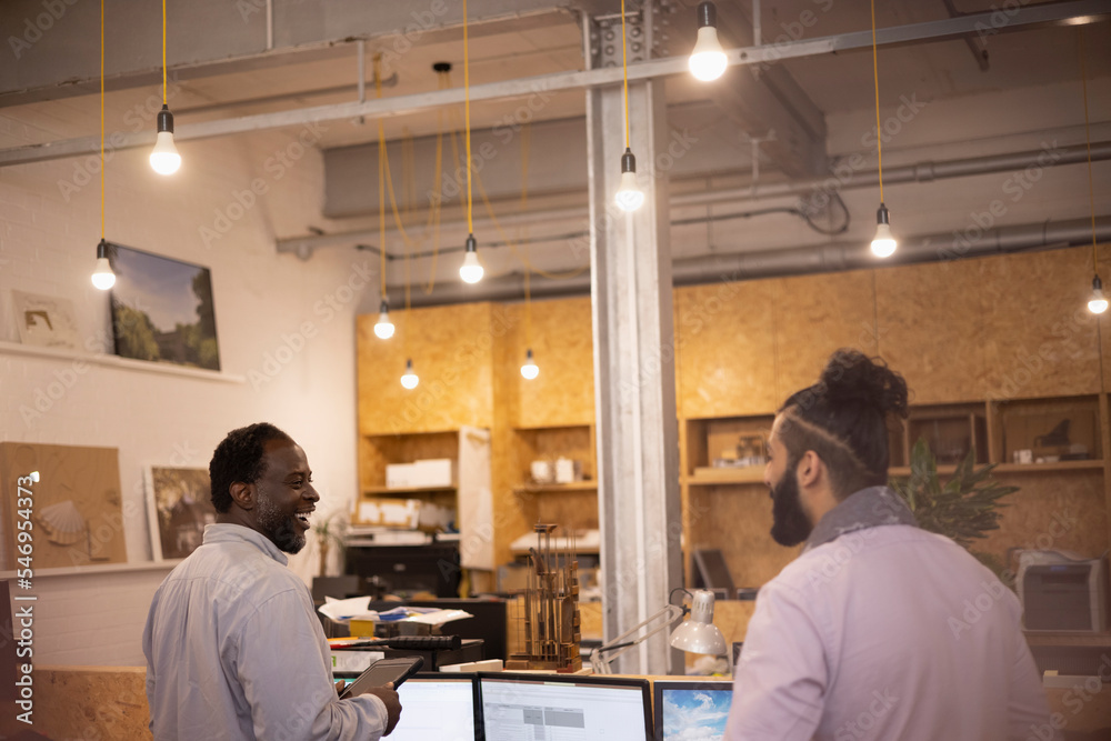 Smiling businessmen talking in open plan office Smiling businessmen talking in open plan office