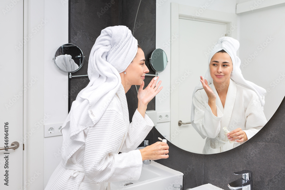 Positive lady applying cream in hotel bathroom