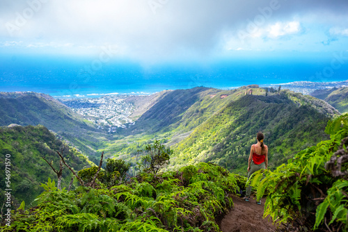 hiker girl enjoys the panorama of oahu island and honolulu in hawaii islands while climbing wiliwilinui ridge trail; hiking on green mountains in hawaii, holidays in hawaii