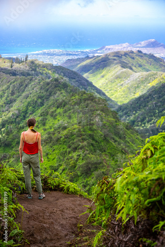 hiker girl enjoys the panorama of oahu island and honolulu in hawaii islands while climbing wiliwilinui ridge trail; hiking on green mountains in hawaii, holidays in hawaii