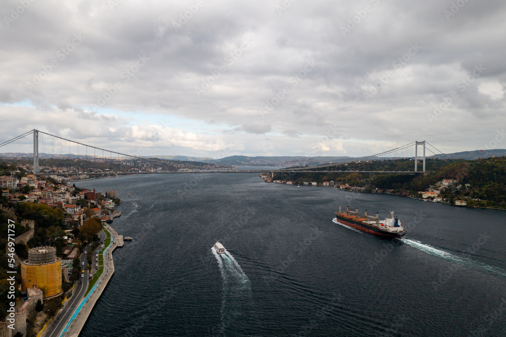 Tanker, cargo ship passes through the Bosporus. Awesome view of the Bosphorus Bridge (the 15 July Martyrs Bridge) connecting Europe to Asia.
