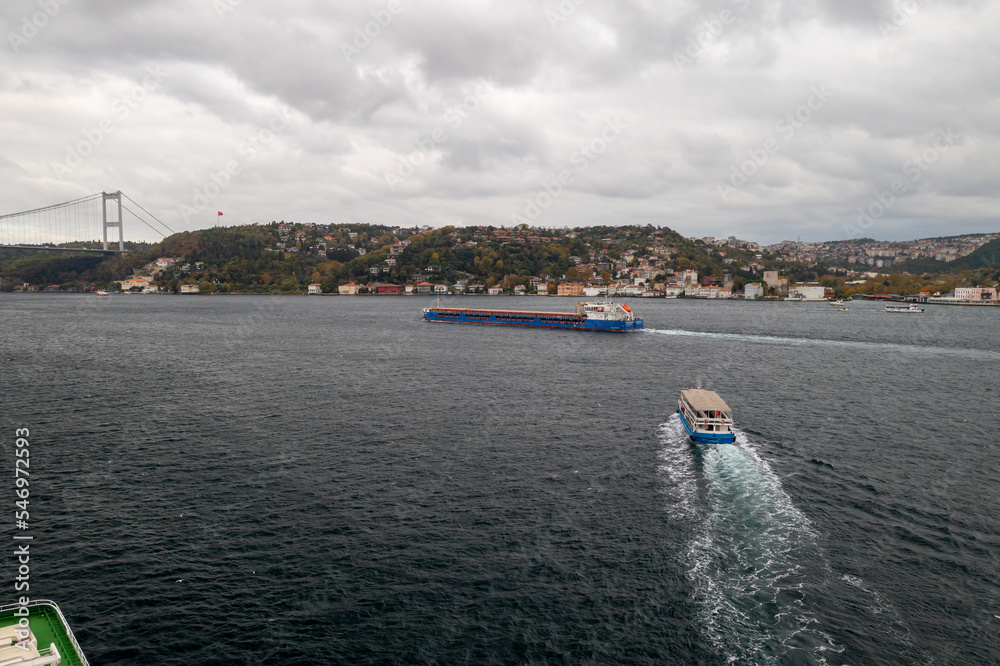 Tanker, cargo ship passes through the Bosporus. Awesome view of the Bosphorus Bridge (the 15 July Martyrs Bridge) connecting Europe to Asia.