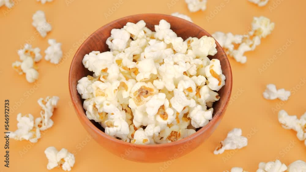 Salty and sweet popcorn falling in wooden bowl, yellow background Salty and sweet popcorn falling in wooden bowl, yellow background
