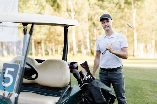 A golfer is going to play golf on the field, he chooses a club. copy space. High quality photo