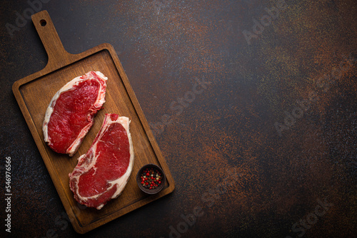 Fotografia Two raw uncooked meat beef rib eye marbled steaks on wooden cutting board with s