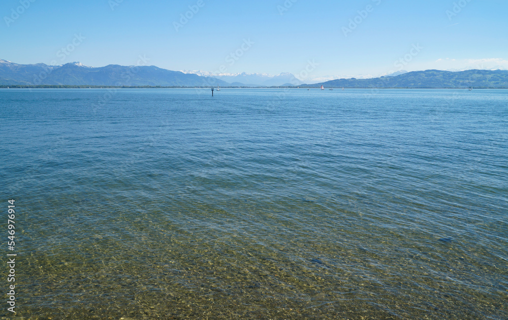 gorgeous blue water of lake Constance (Bodensee) with the Alps in the background seen from the shores of Lindau island on a sunny spring day in Germany gorgeous blue water of lake Constance (Bodensee) with the Alps in the background seen from the shores of Lindau island on a sunny spring day in Germany