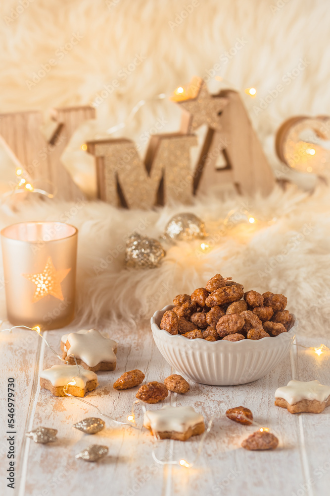 Bowl of sweet candied almonds and cinnamon cookies on white wood with Christmas decoration Bowl of sweet candied almonds and cinnamon cookies on white wood with Christmas decoration