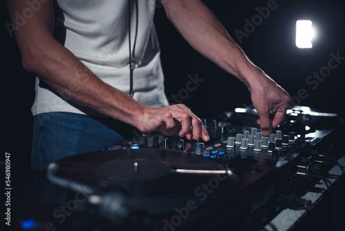 Concert DJ playing music on stage. Nightclub disc jockey mixing music tracks on party