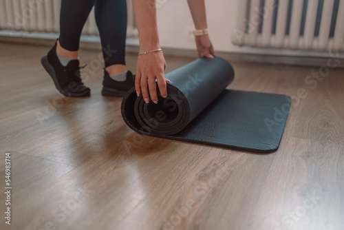 Fitness yoga exercise workout woman. A woman with a yoga mat in a sport room in a bright room. Time for meditation, fitness session, well-being concept. 