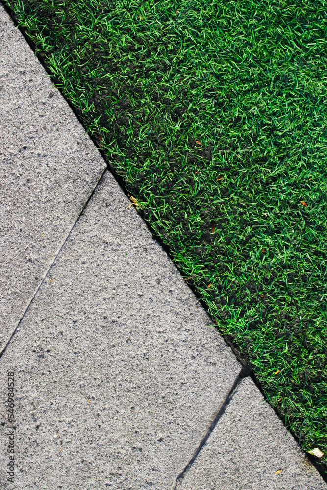 Obraz premium artificial turf and concrete tiles in a walkway in a green lawn.