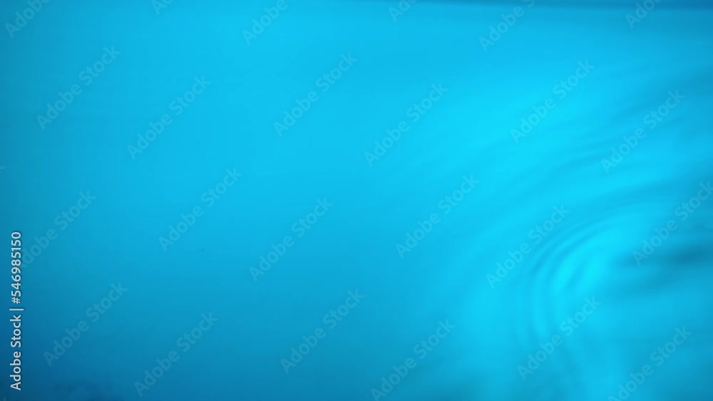Ripples and waves appear on the blue water surface. Macro shot of smooth liquid surface with wave motion of water. Ripples on the surface of the aqua. Vibration of blue liquid. Ripples and waves appear on the blue water surface. Macro shot of smooth liquid surface with wave motion of water. Ripples on the surface of the aqua. Vibration of blue liquid.