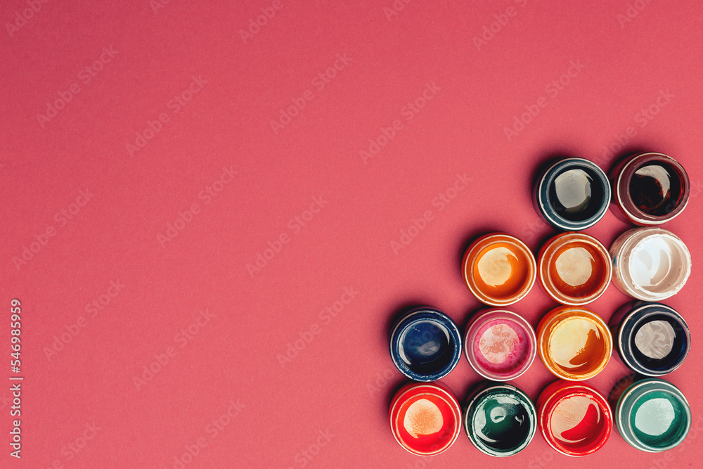 Beautiful, bright, mother-of-pearl, multicolored open cans of paint on a bright pink background. View from above. The concept of creativity. Beautiful, bright, mother-of-pearl, multicolored open cans of paint on a bright pink background. View from above. The concept of creativity.