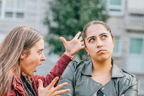 two female friends arguing in the street outdoors