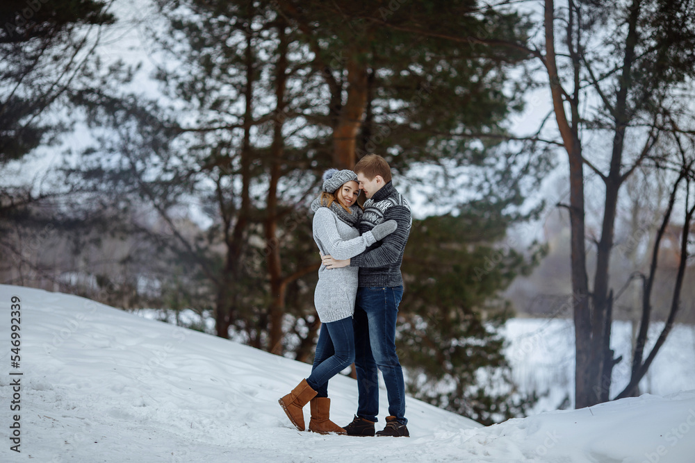 The couple hugs and smiles while standing in the snow. The couple hugs and smiles while standing in the snow.