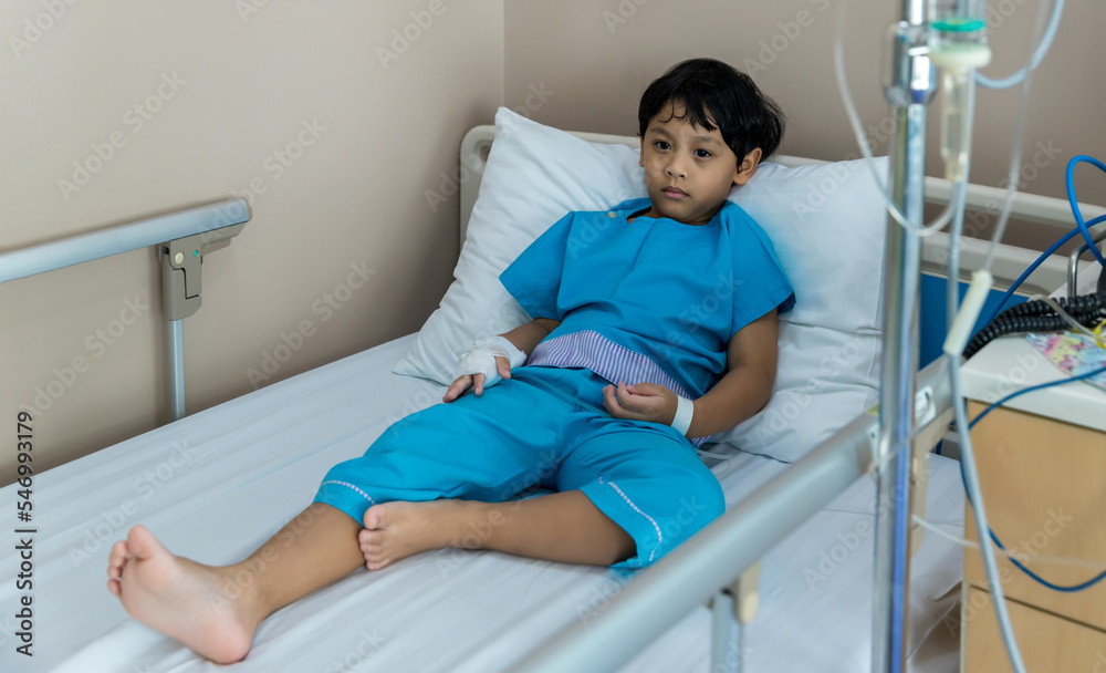 Child patient's hand has get the saline solution syringe on it. Illness and treatment. Sick boy child lying on bed at hospital. Child patient's hand has get the saline solution syringe on it. Illness and treatment. Sick boy child lying on bed at hospital.