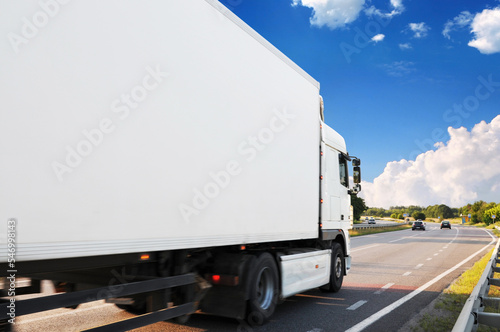 Close-up of the big truck with a trailer on a countryside road against a sky with clouds