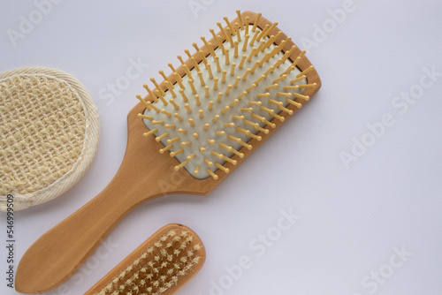 Beauty accessories wooden comb  nail brush  facial sponge on white background. Modern paddle hair brush on table. Top view  flat lay  copy space. 