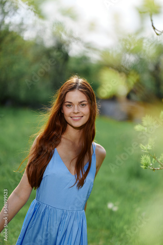 Fototapeta Naklejka Na Ścianę i Meble -  Woman smile with teeth in the spring on a sunny day happily walking in nature against the green grass, the concept of women's body health