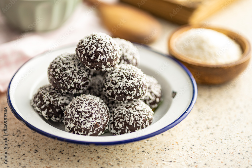 Coconut chocolate balls on plate on kitchen table.