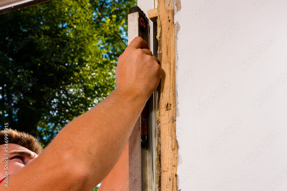 Φωτογραφία The locksmith-installer after fixing the window checks whether it is fixed to the wall, the installation of the window, the master uses the level