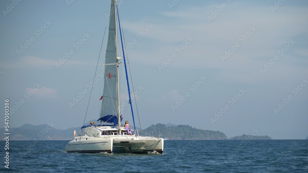 The sailboat glide through blue turquoise calm water of sea. Tropical summer vacation dream. Yacht sailing on opened ocean. Sailing boat yachting video. Yacht sailboat