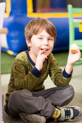 A kid eats a cupcake. Handsome boy has a Happy Birthday party. Portrait of a Preschool smiling Boy.