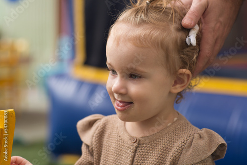 Portrait of a Toddler Girl. Curly girl's profile. Daddy holds baby's had.  