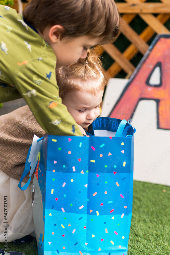 Boy and girl open present. Brother and sister look inside a bag Boy and girl open present. Brother and sister look inside a bag