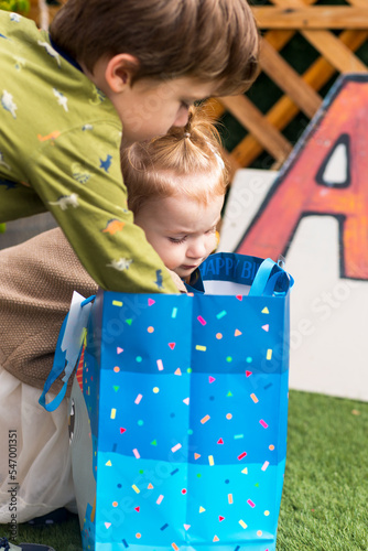 Boy and girl open present. Brother and sister look inside a bag