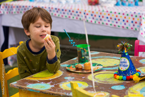 A kid eats a cupcake. Handsome boy has a Happy Birthday party. Portrait of a Preschool smiling Boy.
