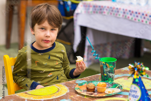 A kid eats a cupcake. Handsome boy has a Happy Birthday party. Portrait of a Preschool smiling Boy.