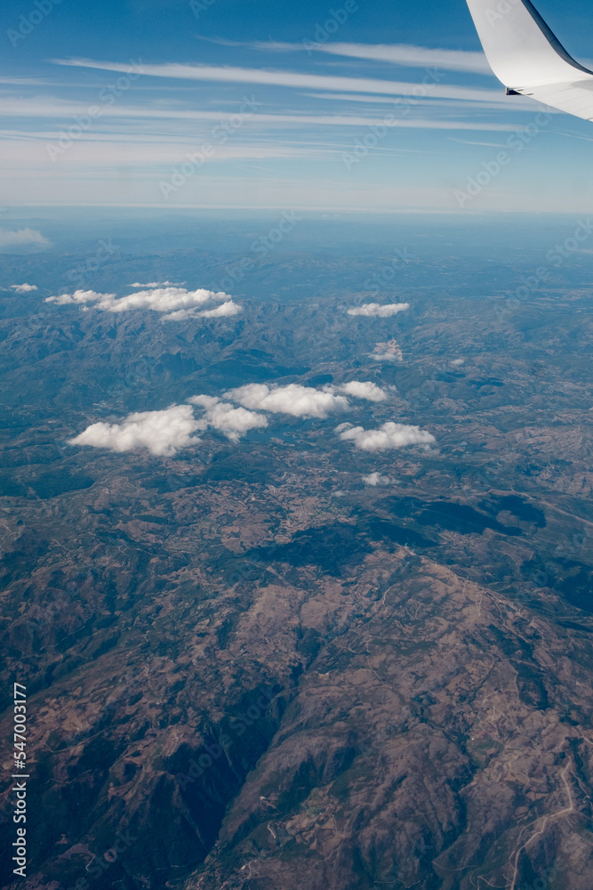Aerial view of a land mountain landscape while flying away with a passenger aircraft scenic view from the window plane