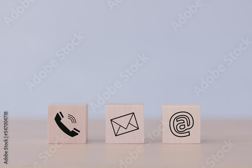 E-mail address, telephone number, and letter icons print screen on the cubic wooden block on the table for webpage business contact and customer service concept. © THAWEERAT