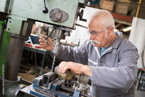 Slika na platnu senior metal worker using industrial drilling machine in workshop