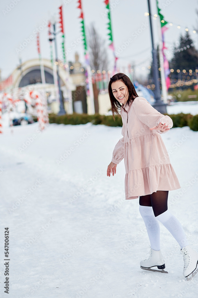 Young stylish woman in dressis ice skating in winter. Festive holidays mood. Young stylish woman in dressis ice skating in winter. Festive holidays mood.