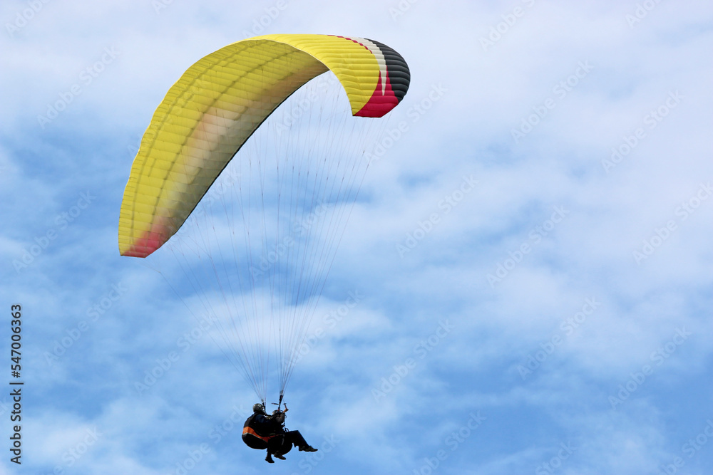 Yellow tandem Paraglider flying in a cloudy sky Yellow tandem Paraglider flying in a cloudy sky