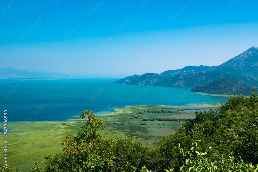 Scenic Viewpoint. Beautiful summer landscape of Skadar Lake with green and blue water, mountains hills. Montenegro. Scenic Viewpoint. Beautiful summer landscape of Skadar Lake with green and blue water, mountains hills. Montenegro.