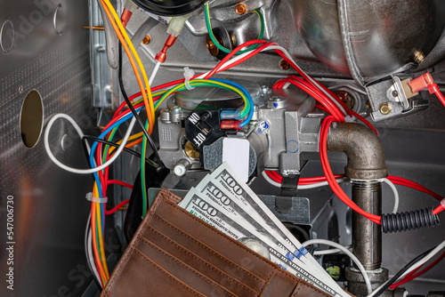Furnace circuit control board and cash money in wallet. HVAC maintenance, repair, service and installation concept. © JJ Gouin