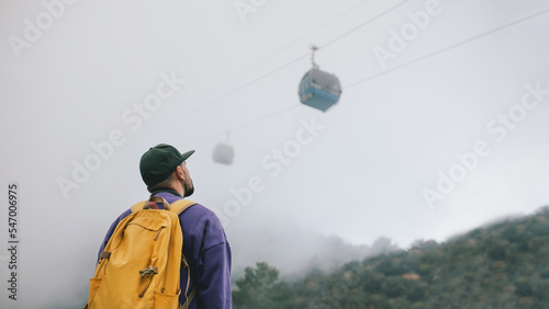 Man with a backpack stands on top of a mountain next to the funicular.