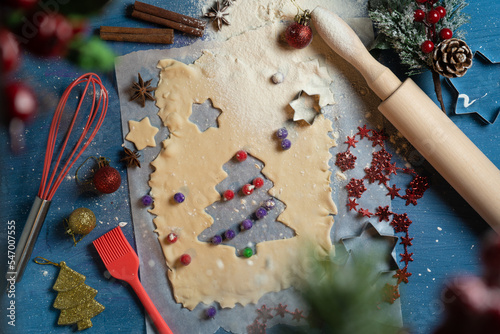 Christmas, New Year cooking, traditional gingerbread cookies preparaion. Top view on dough, kitchenware, holiday decorations. Christmas trees made of cookie cutter and berries Food design idea, flatly photo