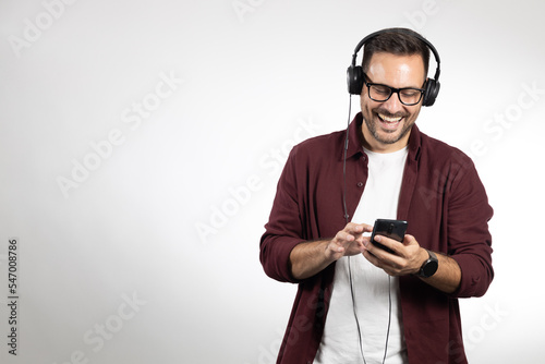 Young casual dressed man enjoying in his favourite music. Studio portrait photo, taken on white background