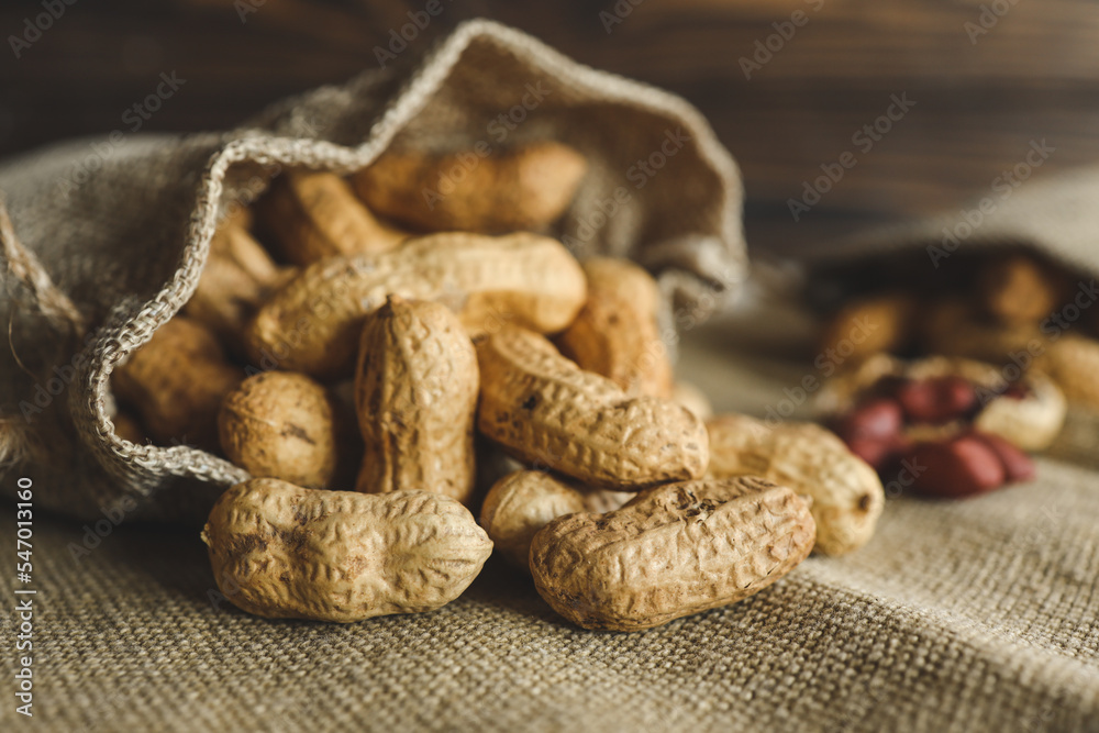 Fototapeta premium Peanuts in a bag on a woody background